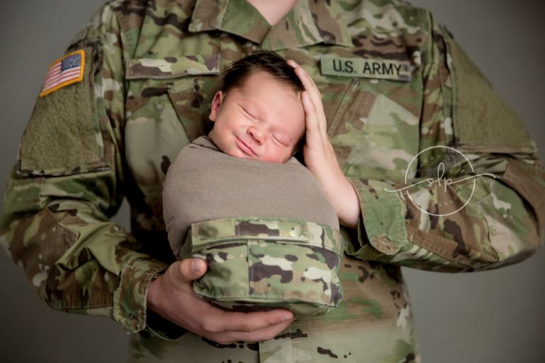 Army soldier holding smiling newborn baby
