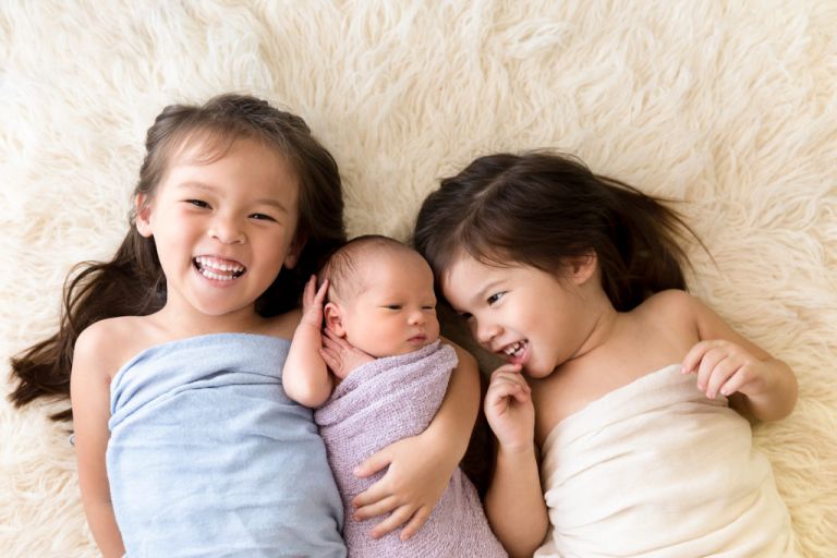 two young girls with baby newborn baby sister