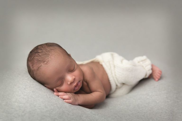 newborn baby boy with white pants sleeping