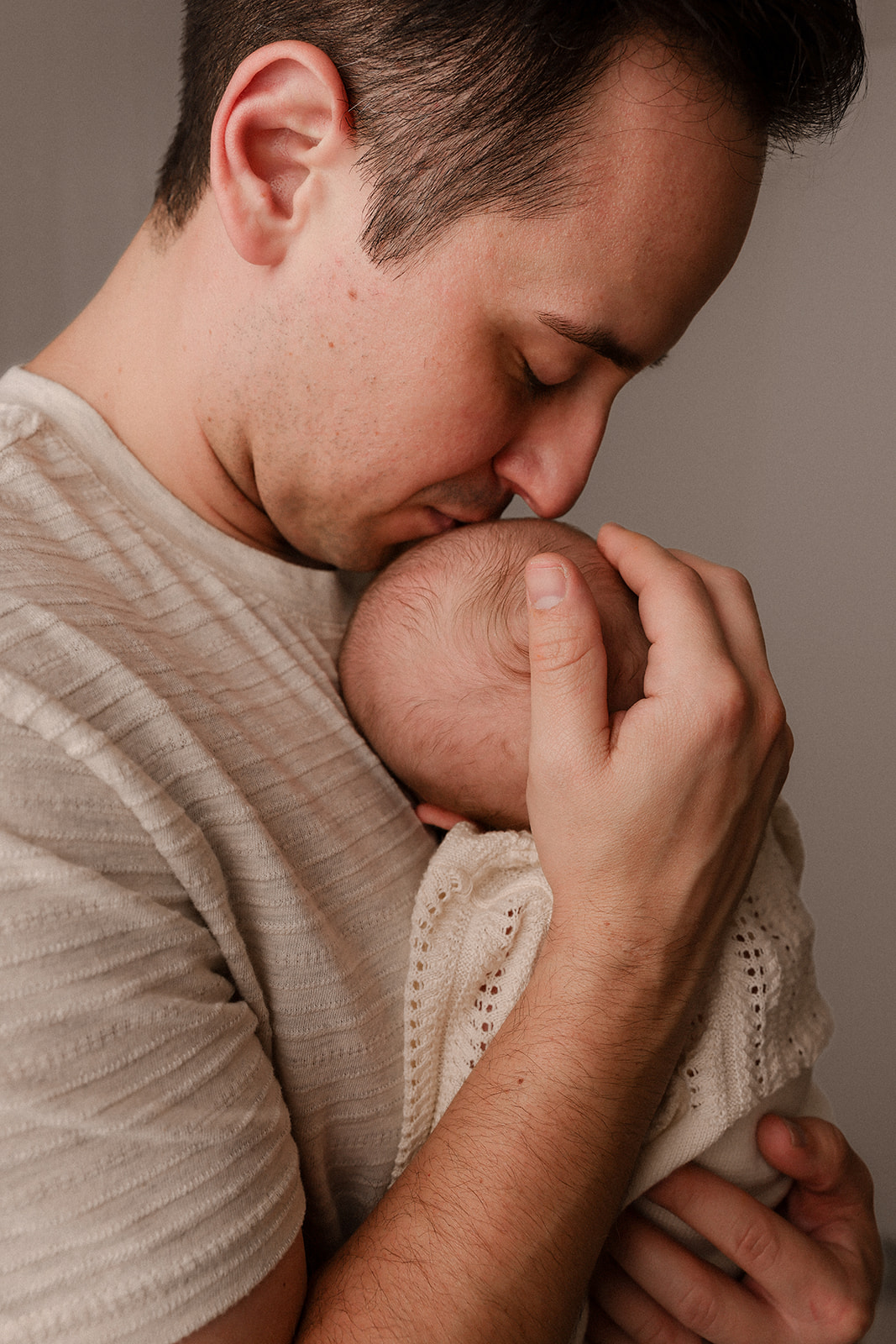 a father holding and kissing his newborn son's head
