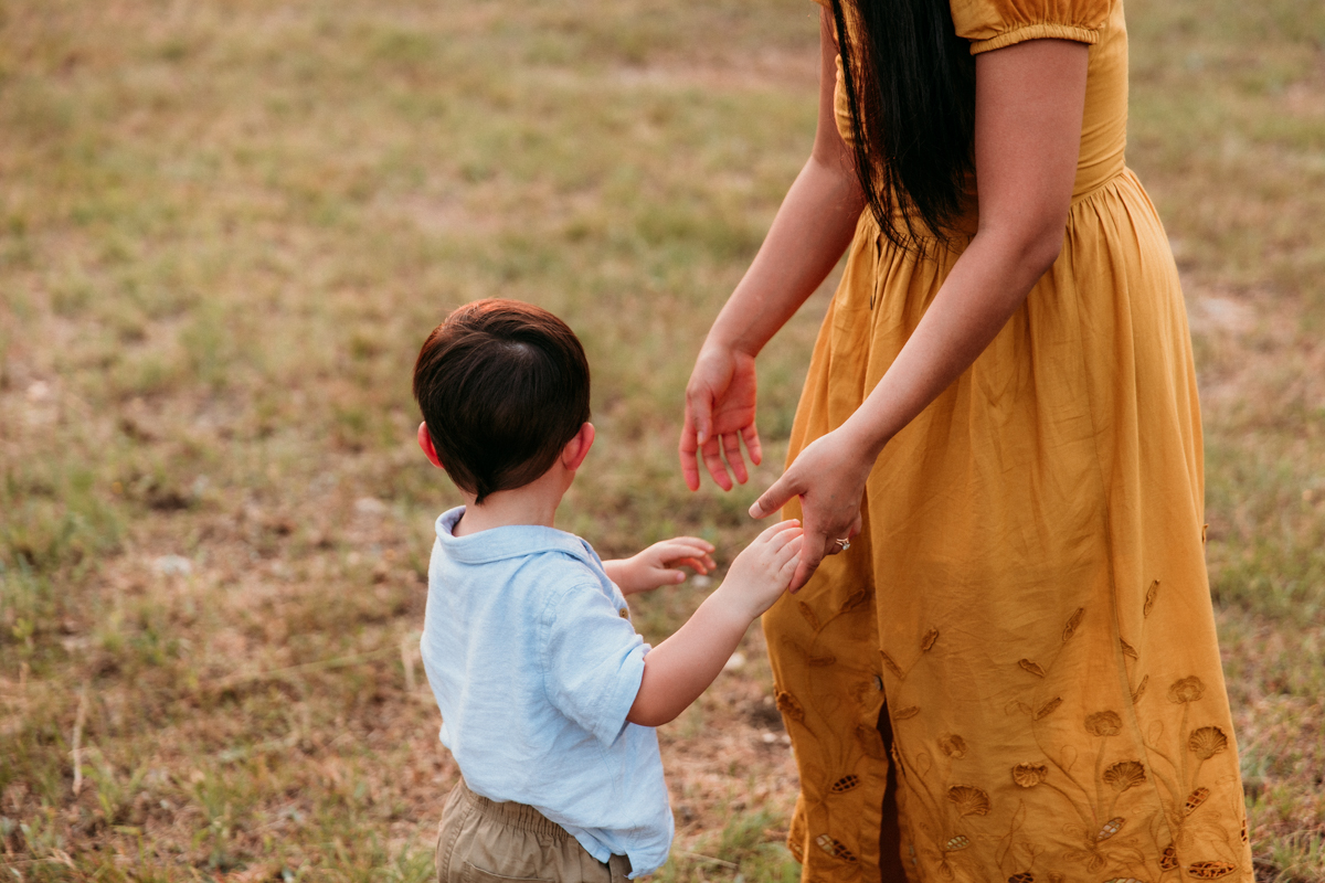 little boy reaching for his mother's hand