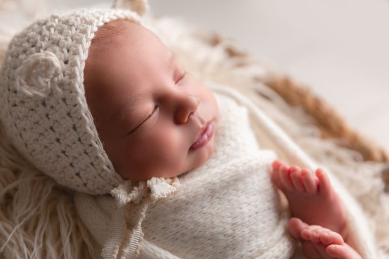 close up of a newborn with a white bonnet