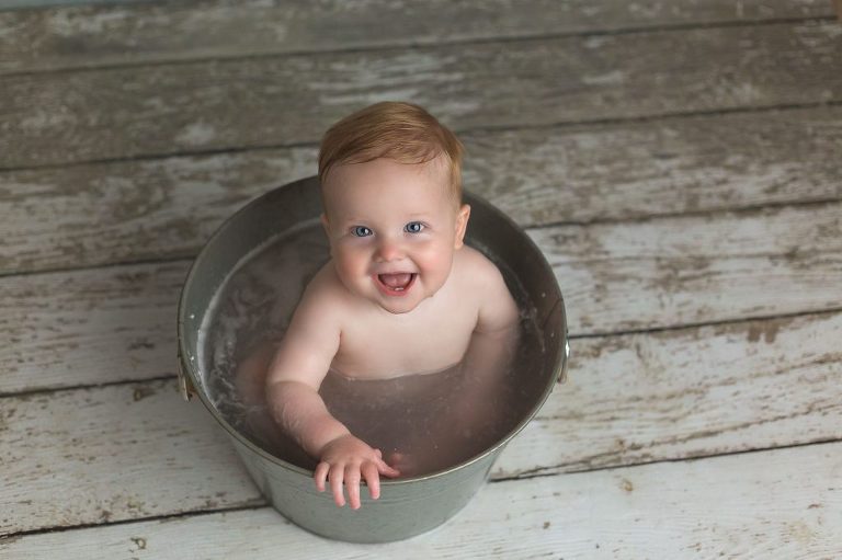 Smiling baby bathing in a washtub