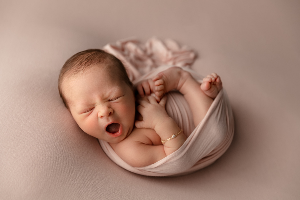 baby girl swaddled in pink sleeping and yawning