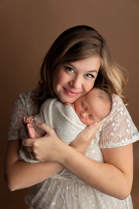 pretty mom dressed in white holding newborn baby 