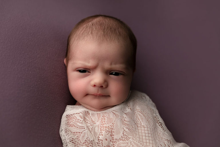 Newborn baby girl with eyes open make a scowly face