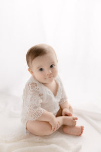 smiling baby girl sitting in front of lit up curtain