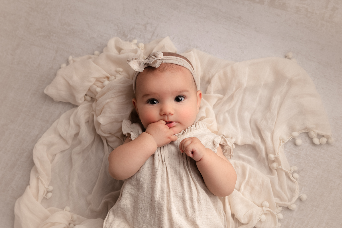 3 month old baby girl with her finger in her mouth